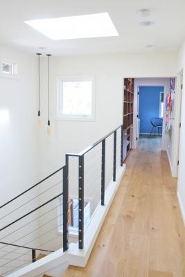 The modern stairway of the Berkeley bungalow leads to the open hallway on the second floor