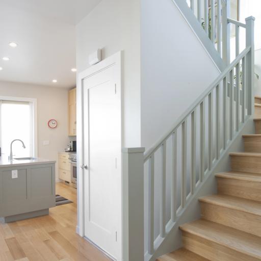 The kitchen is seen in the background of this photo featuring the transitional staircase. 
