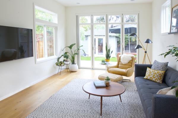 The open plan living room of the Berkeley bungalow is flooded with light from large windows and sliding glass doors
