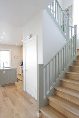 The kitchen is seen in the background of this photo featuring the transitional staircase. 