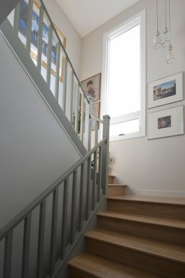 The bright stairway features the same gray trim and light wood floors creating a cohesive space. A large window and framed artwork on the walls completes the landing.